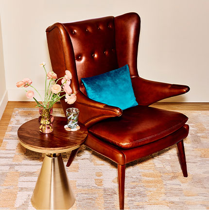 A living room featuring a leather wingback chair & a stylish wooden coffee table.